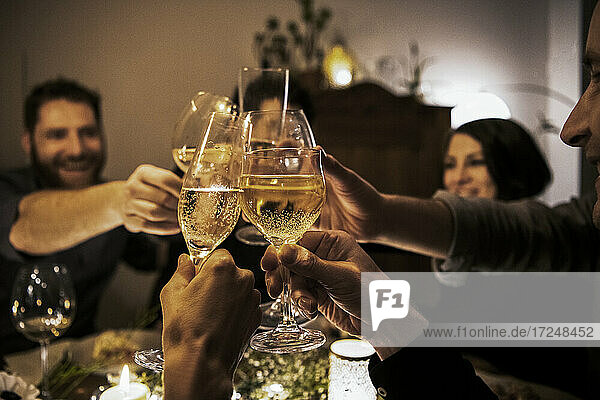 Cheerful friends raising toasts during birthday celebration at home