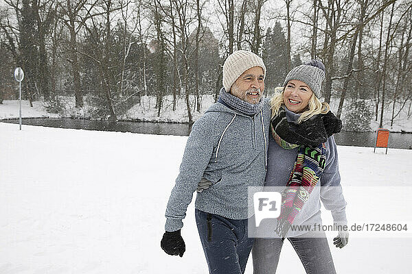 Senior man with arm around woman walking in park