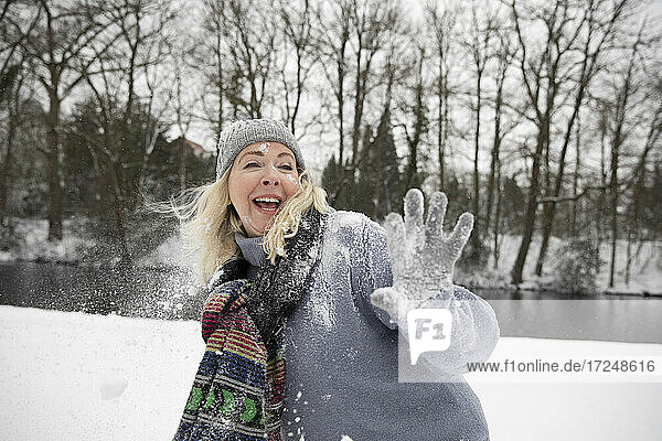 Ältere Frau spielt im Winter mit Schneeball