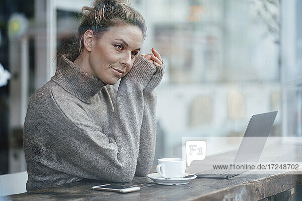 Mid adult business person contemplating while sitting by cafe window