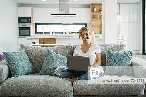 Geschäftsfrau mit Laptop  während sie zu Hause auf dem Sofa sitzt
