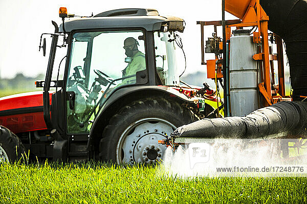 Männlicher Landwirt im Traktor beim Sprühen von Fungiziden auf Pflanzen