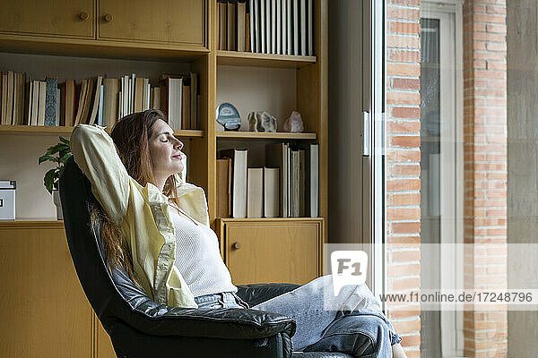 Entspannte Frau sitzt auf einem Stuhl zu Hause