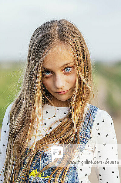 Blondes Mädchen mit blauen Augen steht auf einem Feld