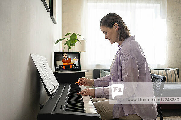 Frau lernt Klavier während eines Online-Tutorials auf ihrem Laptop zu Hause