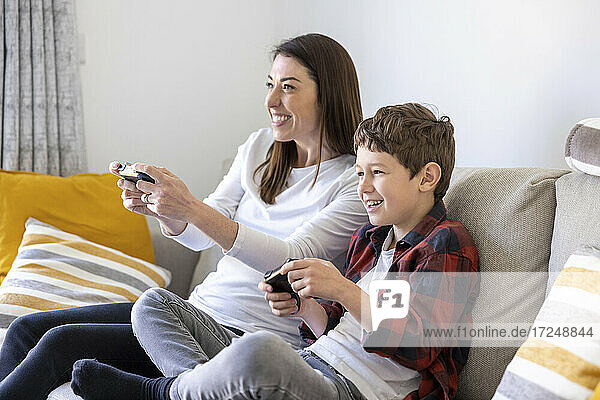 Happy woman with son playing video game on sofa at home