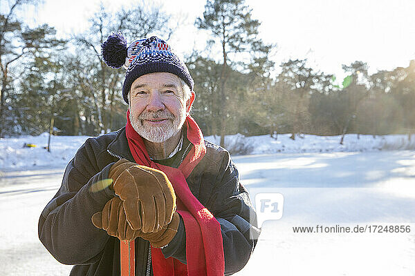 Senior man wearing gloves holding hockey stick outdoors