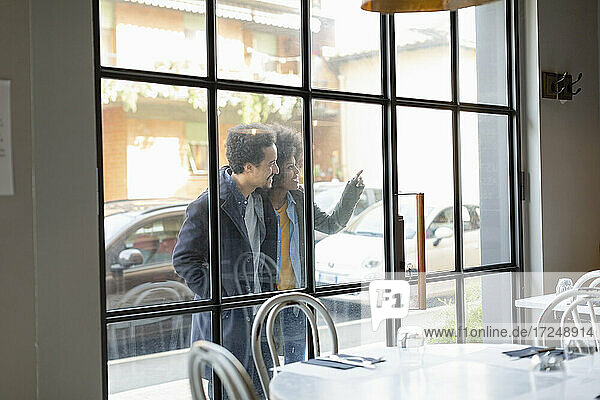 Freund und Freundin schauen durch ein Fenster  während sie vor einem Café stehen