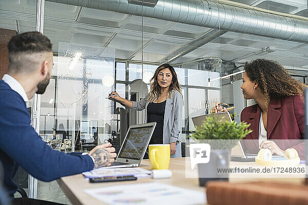 Geschäftsfrau bespricht Geschäftsplan mit männlichen und weiblichen Kollegen in einem Coworking-Büro