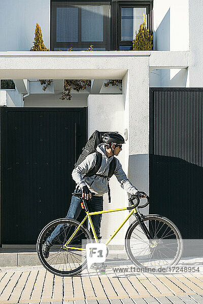 Zusteller mit Fahrrad auf dem Fußweg vor dem Haus