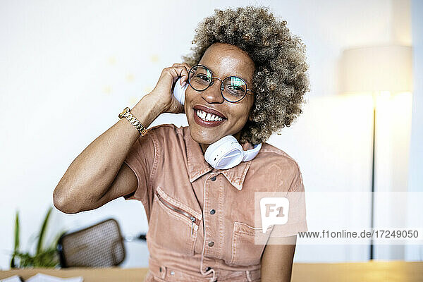 Businesswoman with eyeglasses holding headphones at home office