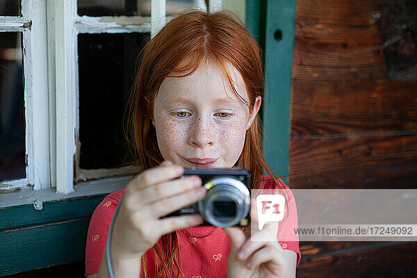 Rothaariges Mädchen fotografiert durch die Kamera am Fenster