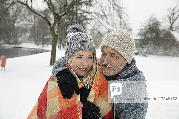 Man embracing woman in blanket during winter