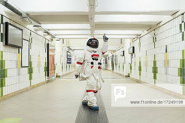 Female astronaut pointing while standing in subway