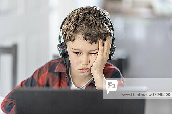 Boy getting bored during online classes attending at home