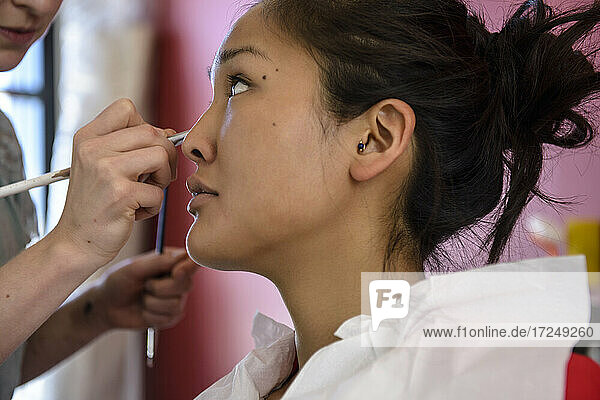 Maskenbildnerin trägt Make-up auf ein Modell im Studio auf