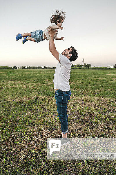 Playful man playing with baby boy while standing on grass