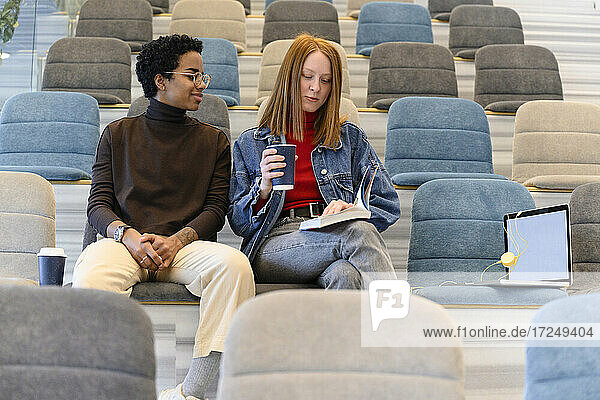 Multi-ethnic female friends sitting in auditorium