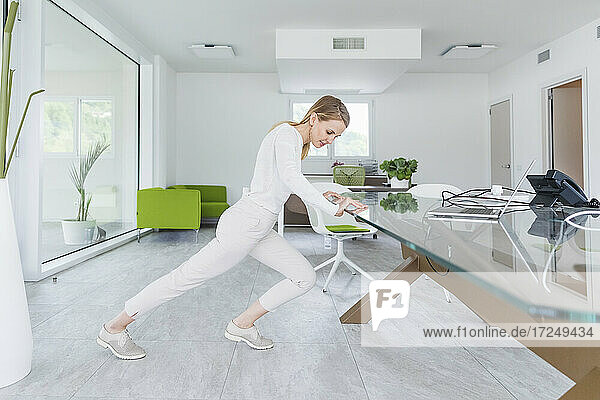 Businesswoman stretching over conference table at office