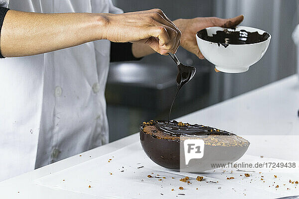 Bäckerin gießt Schokolade auf ein Dessert in der Küche