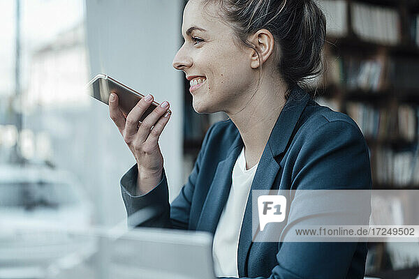 Lächelnde Geschäftsfrau  die in einem Café mit einem Mobiltelefon spricht