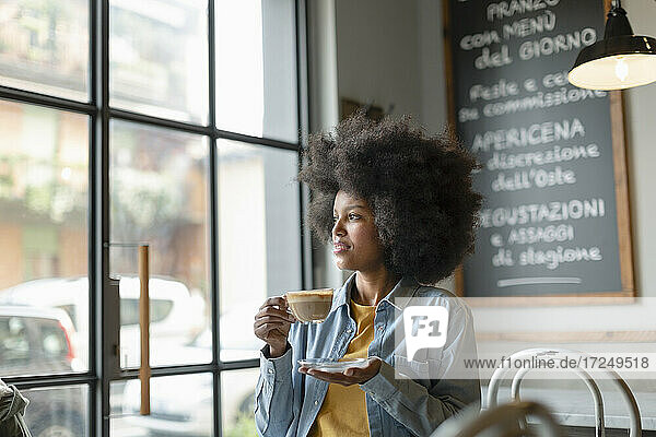 Weibliche Fachkraft schaut weg und hält eine Kaffeetasse in einem Café