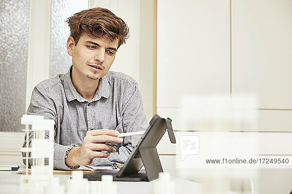 Young male architect working over digital tablet at table
