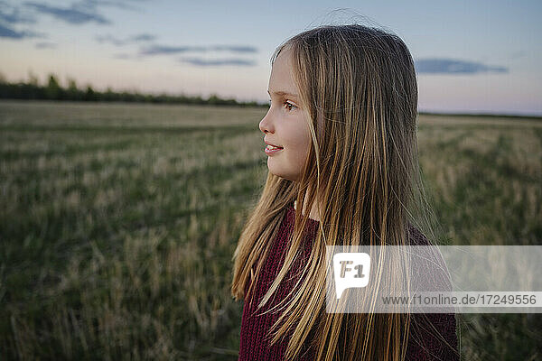 Blondes Mädchen schaut bei Sonnenuntergang in einem Feld weg