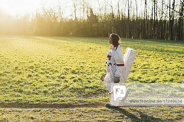 Weibliche Astronautin im Raumanzug  die an einem sonnigen Tag durch Grasland spaziert