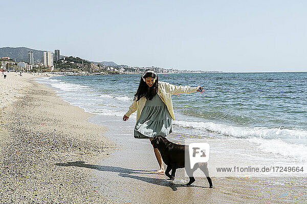 Frau spielt am Wochenende mit Labrador-Hund am Strand