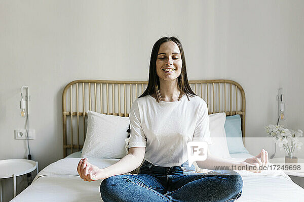 Woman in lotus position on bed at home