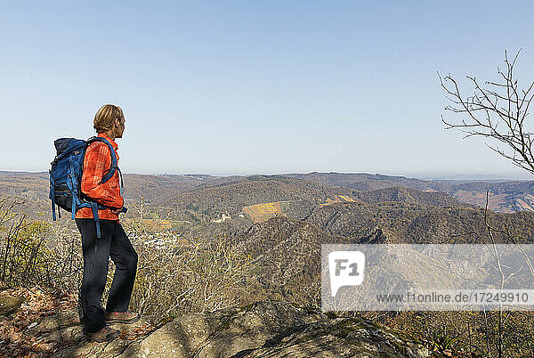 Female hiker admiring landscape of Ahr Valley from edge of cliff