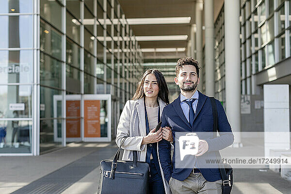 Smiling business couple looking away while standing together on footpath