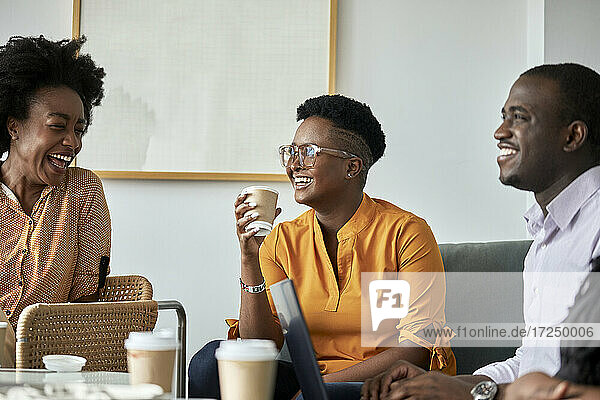 Glückliche männliche und weibliche Fachkräfte diskutieren in der Kaffeepause im Büro