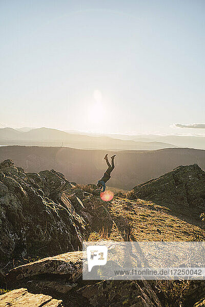 Mid adult sportsman doing handstand while exercising on mountain