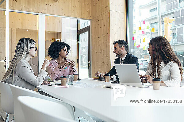 Männliche und weibliche Unternehmer diskutieren am Konferenztisch im Büro