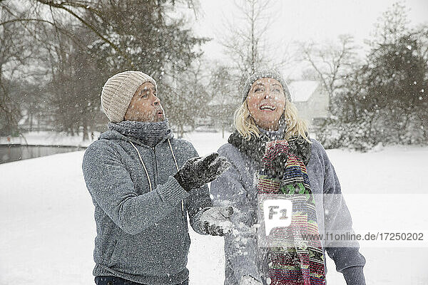 Senior couple throwing snow while playing during winter