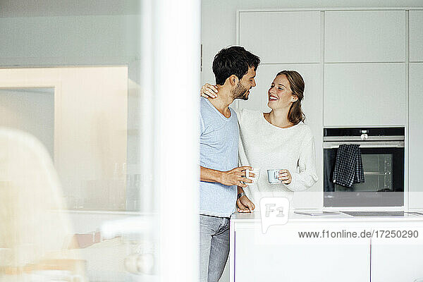 Glückliches junges Paar  das sich in der Küche stehend ansieht