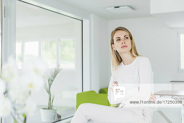Businesswoman with arms crossed day dreaming while sitting at office