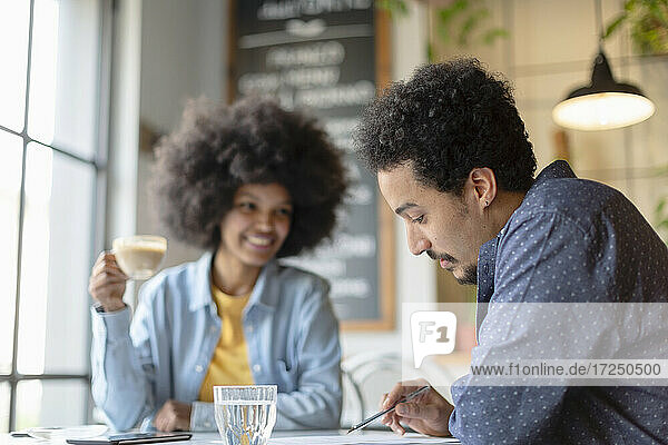 Mann liest Vertrag  während er mit einer Geschäftsfrau in einem Café sitzt