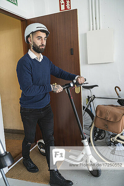 Businessman with electric push scooter arriving in office