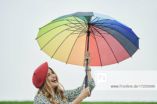 Lächelnde Frau hält mehrfarbigen Regenschirm