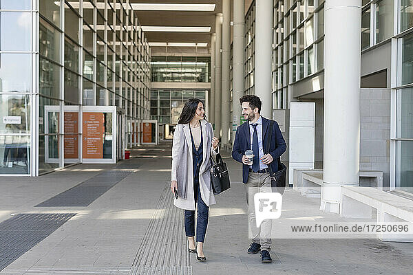 Male and female colleagues talking while walking on footpath