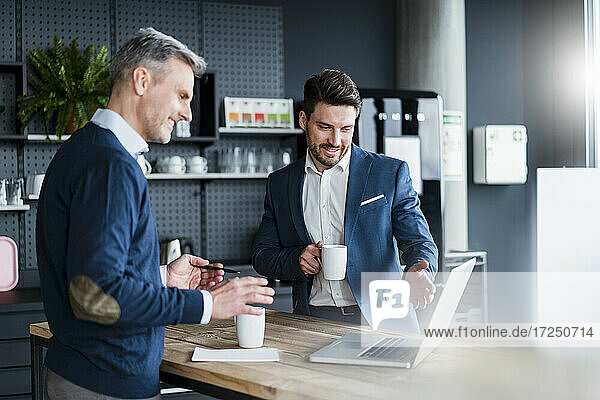 Geschäftsleute diskutieren am Laptop bei einem Kaffee im Bürocafé
