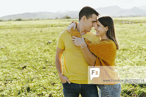 Happy girlfriend embracing boyfriend standing in grass