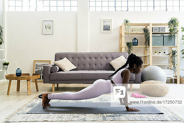 Junge Frau macht Yoga im Wohnzimmer zu Hause