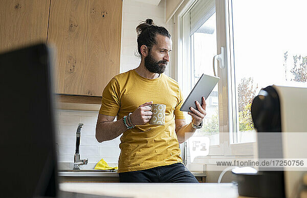 Älterer Mann mit digitalem Tablet in der Küche zu Hause