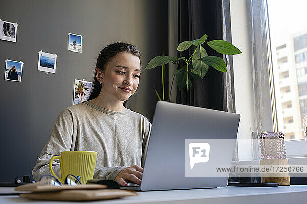 Young woman using laptop while working at home