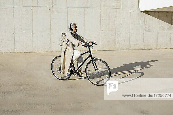 Ältere Frau fährt mit dem Fahrrad auf einem Fußweg an einem sonnigen Tag