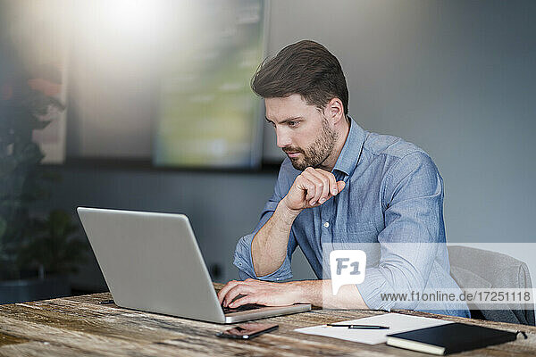Mid adult male entrepreneur working on laptop over table in office